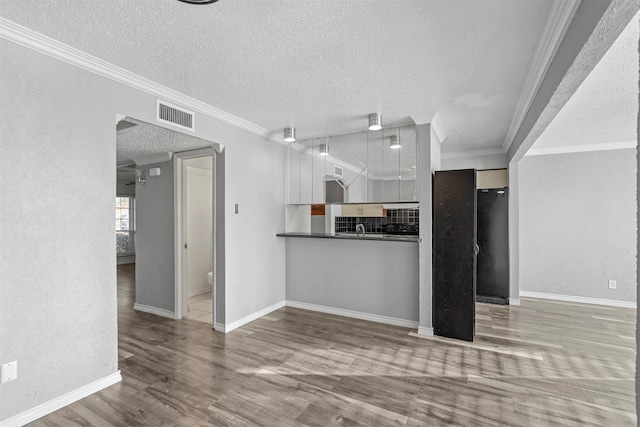 kitchen with white cabinets, light hardwood / wood-style flooring, ornamental molding, and tasteful backsplash