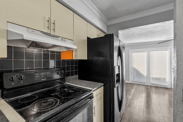 kitchen featuring decorative backsplash, cream cabinetry, black appliances, crown molding, and hardwood / wood-style floors