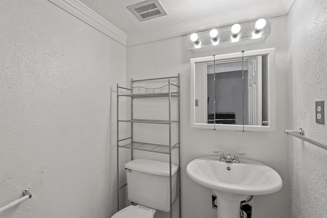 bathroom featuring a textured ceiling, crown molding, toilet, and sink