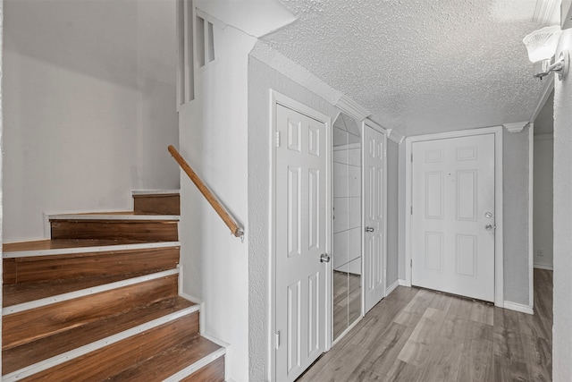 staircase featuring a textured ceiling and hardwood / wood-style flooring