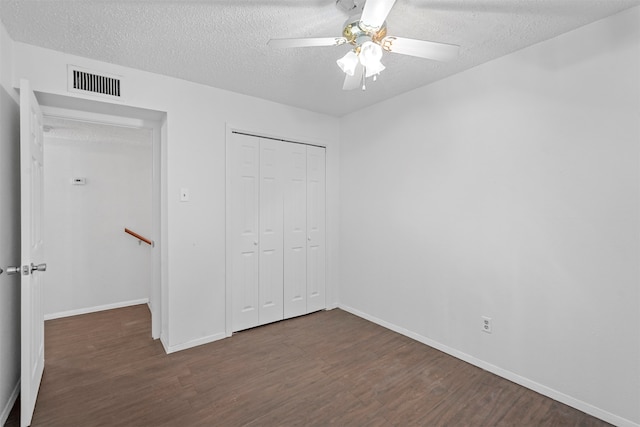 unfurnished bedroom featuring ceiling fan, a textured ceiling, a closet, and dark hardwood / wood-style floors