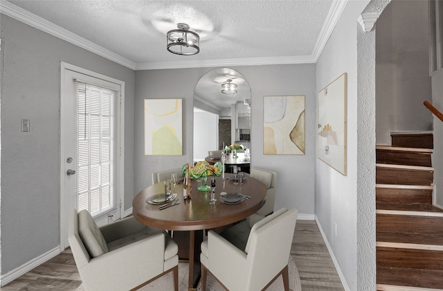 dining area featuring wood-type flooring, a textured ceiling, and crown molding