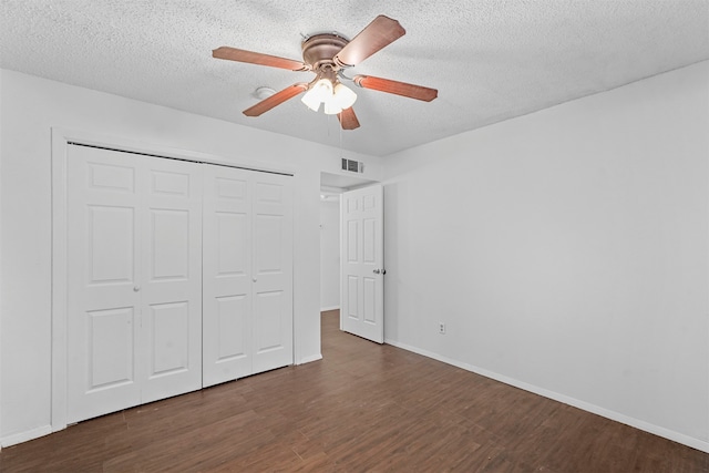 unfurnished bedroom featuring ceiling fan, a textured ceiling, a closet, and dark hardwood / wood-style floors