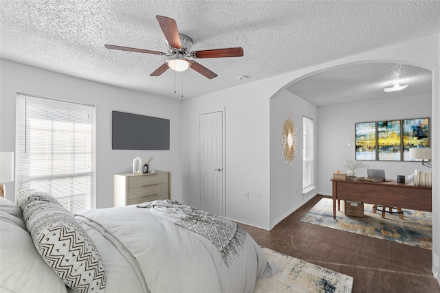 bedroom with ceiling fan, a textured ceiling, and dark hardwood / wood-style flooring