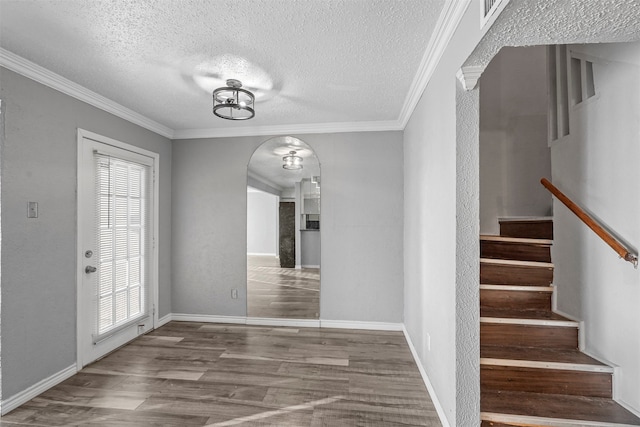 unfurnished dining area featuring hardwood / wood-style flooring, ornamental molding, and a textured ceiling