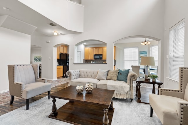 living room featuring a towering ceiling, an inviting chandelier, and hardwood / wood-style flooring