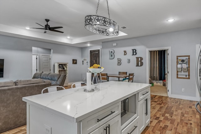 kitchen featuring pendant lighting, a kitchen island, light hardwood / wood-style flooring, a breakfast bar area, and white cabinets