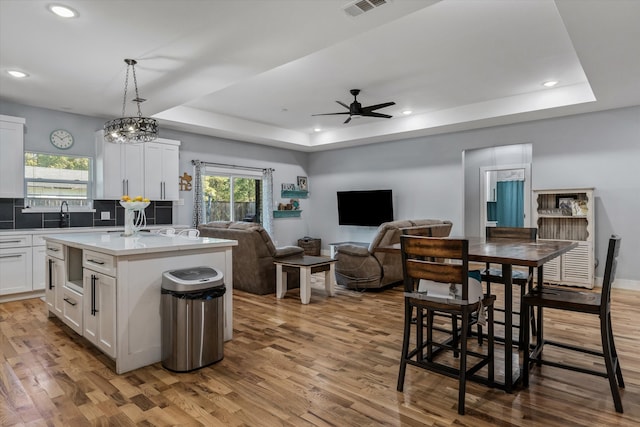 kitchen featuring white cabinetry, a raised ceiling, hanging light fixtures, and a kitchen island