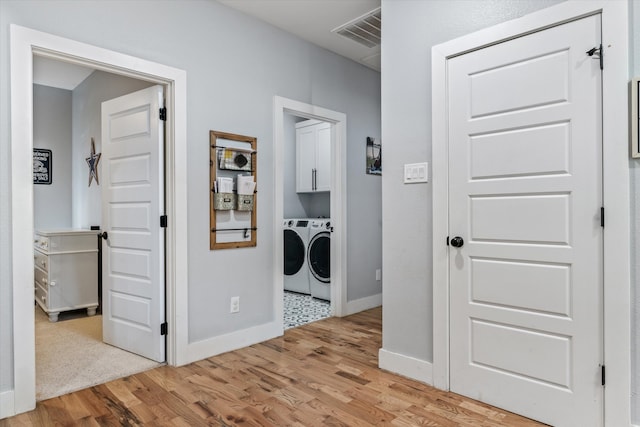 laundry area featuring cabinets, washing machine and clothes dryer, and light wood-type flooring