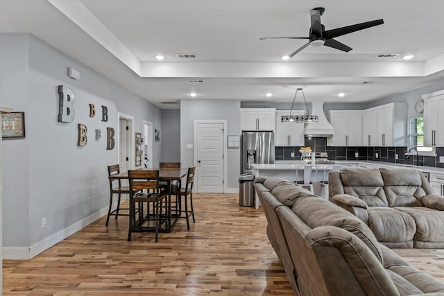 living room with ceiling fan, sink, and light hardwood / wood-style floors