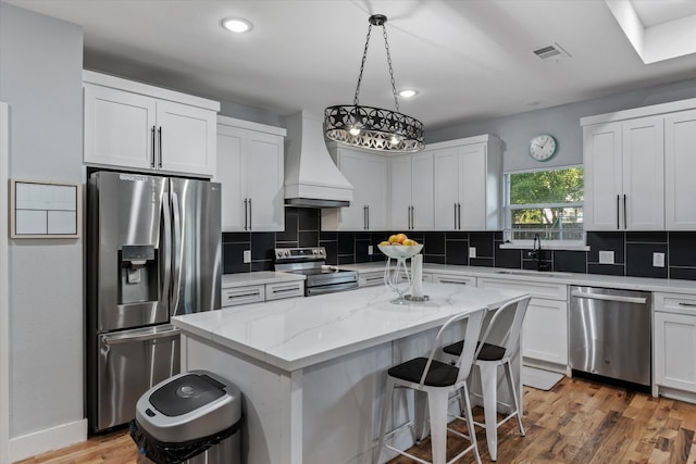 kitchen with a kitchen island, custom exhaust hood, sink, appliances with stainless steel finishes, and white cabinets