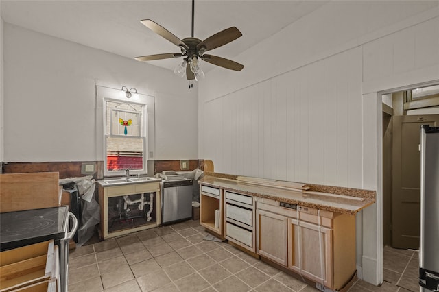 kitchen with sink, wooden walls, tile patterned flooring, ceiling fan, and appliances with stainless steel finishes