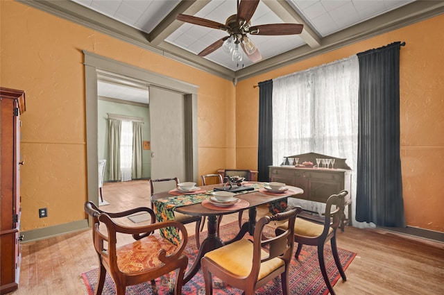 dining area featuring ceiling fan, a textured wall, light wood-style floors, and beam ceiling