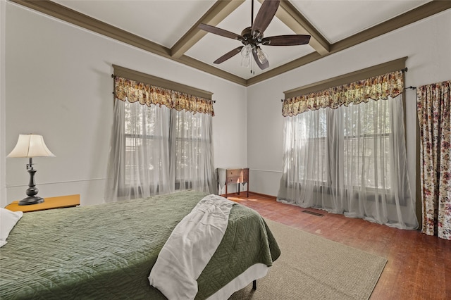 bedroom featuring hardwood / wood-style flooring, beam ceiling, ceiling fan, and multiple windows