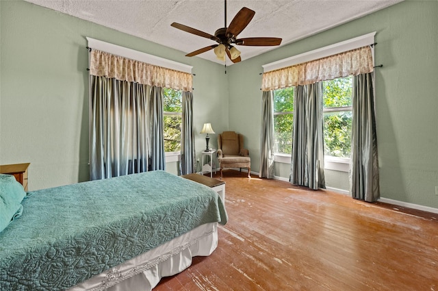 bedroom featuring baseboards, a ceiling fan, a textured ceiling, and hardwood / wood-style floors