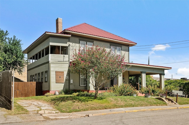 view of front of home featuring metal roof, fence, and a chimney