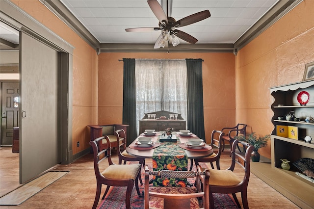dining area with a ceiling fan, a textured wall, and wood finished floors