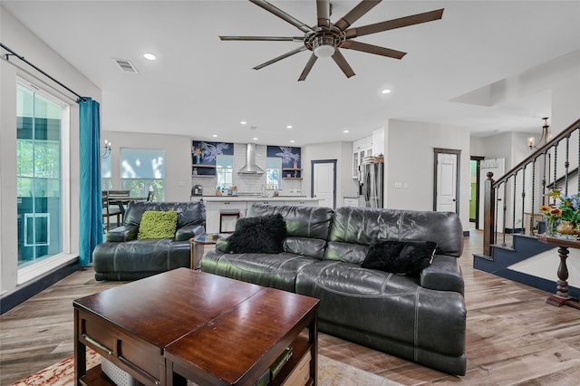 living room with light hardwood / wood-style floors and ceiling fan with notable chandelier