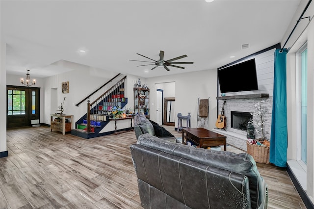 living room with a stone fireplace, a wealth of natural light, and light wood-type flooring