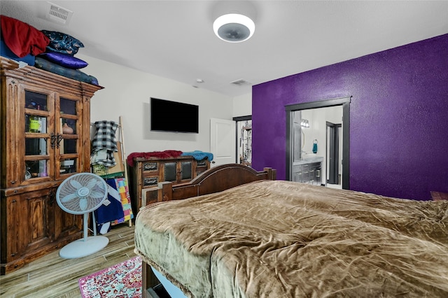 bedroom featuring light hardwood / wood-style flooring and ensuite bathroom