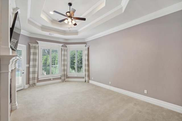 carpeted spare room with a tray ceiling, ceiling fan, and ornamental molding