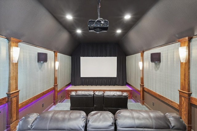 home theater room with light colored carpet and vaulted ceiling