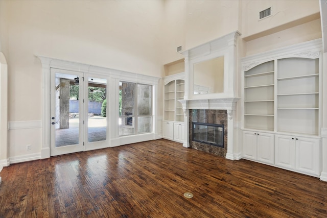 unfurnished living room featuring dark hardwood / wood-style flooring, built in features, and a high end fireplace