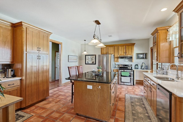 kitchen featuring appliances with stainless steel finishes, hanging light fixtures, tasteful backsplash, a center island, and sink