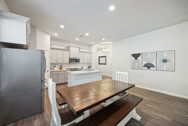 dining area with dark wood-type flooring, an inviting chandelier, and sink