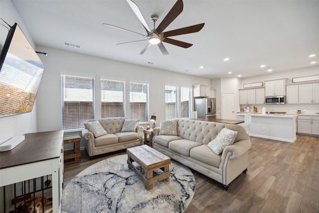 living room with dark wood-type flooring and ceiling fan