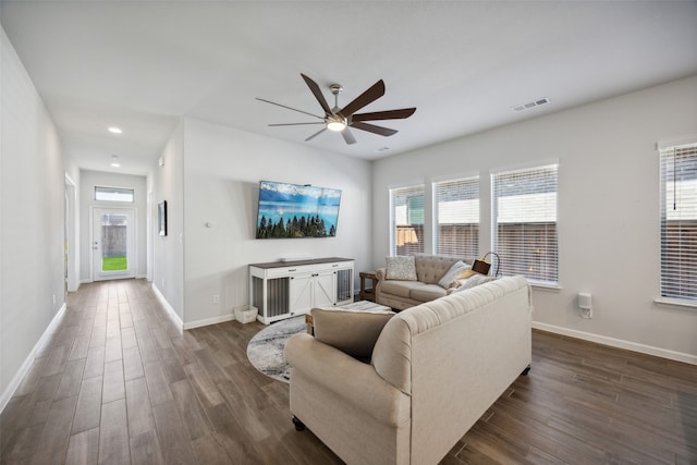 living room with dark wood-type flooring, ceiling fan, and a healthy amount of sunlight