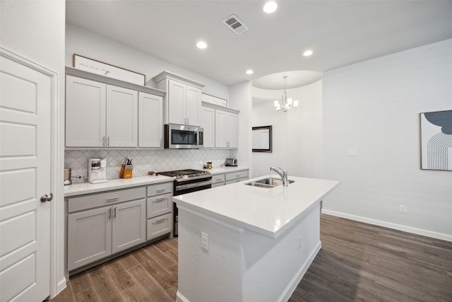 kitchen with sink, tasteful backsplash, gray cabinetry, appliances with stainless steel finishes, and dark hardwood / wood-style floors