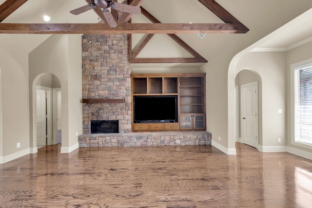 unfurnished living room with high vaulted ceiling, a fireplace, beamed ceiling, ceiling fan, and hardwood / wood-style flooring