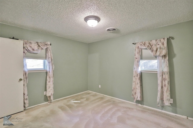 carpeted empty room featuring a textured ceiling