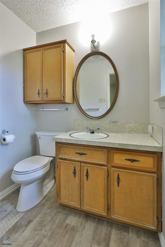 bathroom with vanity, wood-type flooring, a textured ceiling, and toilet