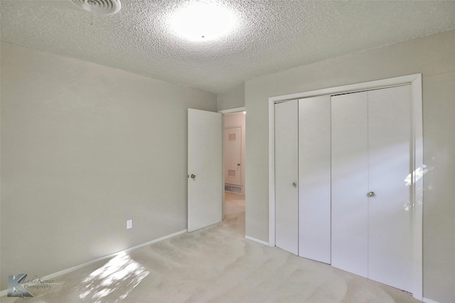 unfurnished bedroom featuring light carpet, a closet, and a textured ceiling