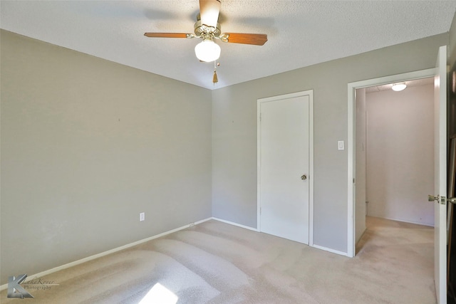 unfurnished bedroom featuring light carpet, a textured ceiling, and ceiling fan