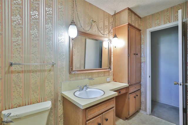 bathroom featuring tile patterned flooring, vanity, toilet, and a textured ceiling