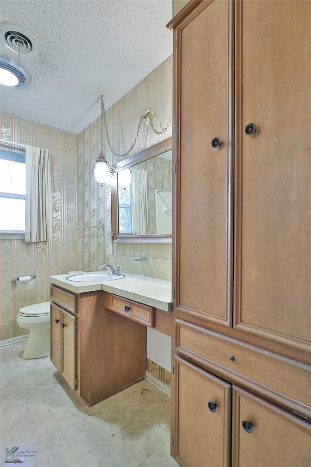 bathroom featuring vanity, toilet, and a textured ceiling