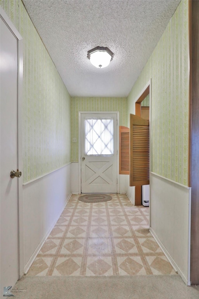 doorway to outside with a textured ceiling