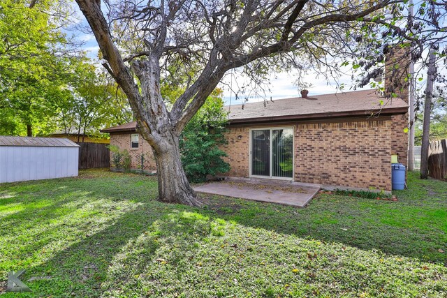 back of property featuring a yard, a patio, and a storage unit