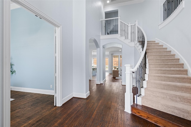 entryway with dark hardwood / wood-style flooring and a towering ceiling