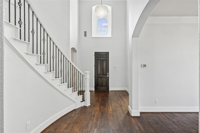 entrance foyer with an inviting chandelier, ornamental molding, dark hardwood / wood-style floors, and a high ceiling