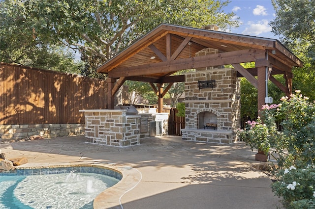 view of patio featuring pool water feature, exterior kitchen, and an outdoor stone fireplace