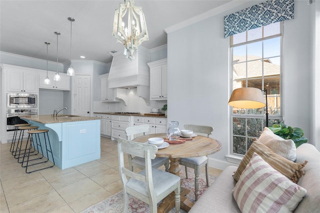 kitchen with hanging light fixtures, white cabinetry, appliances with stainless steel finishes, and a kitchen island with sink