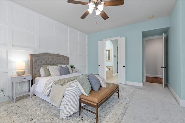 bedroom with ceiling fan, light carpet, and ensuite bath