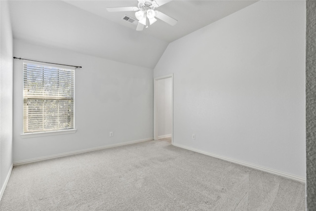 spare room featuring light carpet, lofted ceiling, and ceiling fan