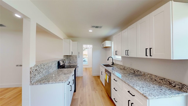 kitchen with light hardwood / wood-style flooring, stainless steel appliances, white cabinetry, and light stone counters