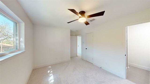 empty room with ceiling fan and light carpet