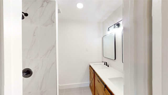 bathroom featuring tiled shower, vanity, and tile patterned flooring